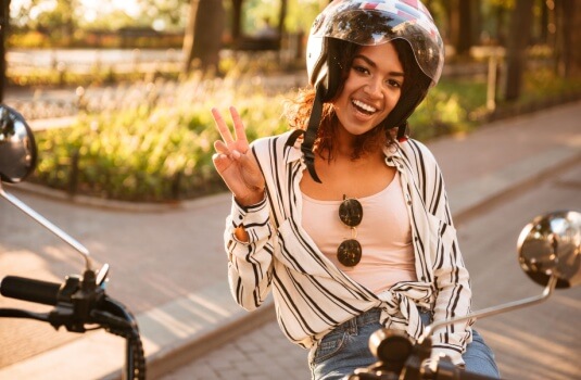 African American woman smiling and waving happily for having motorcycle safety for beginners.