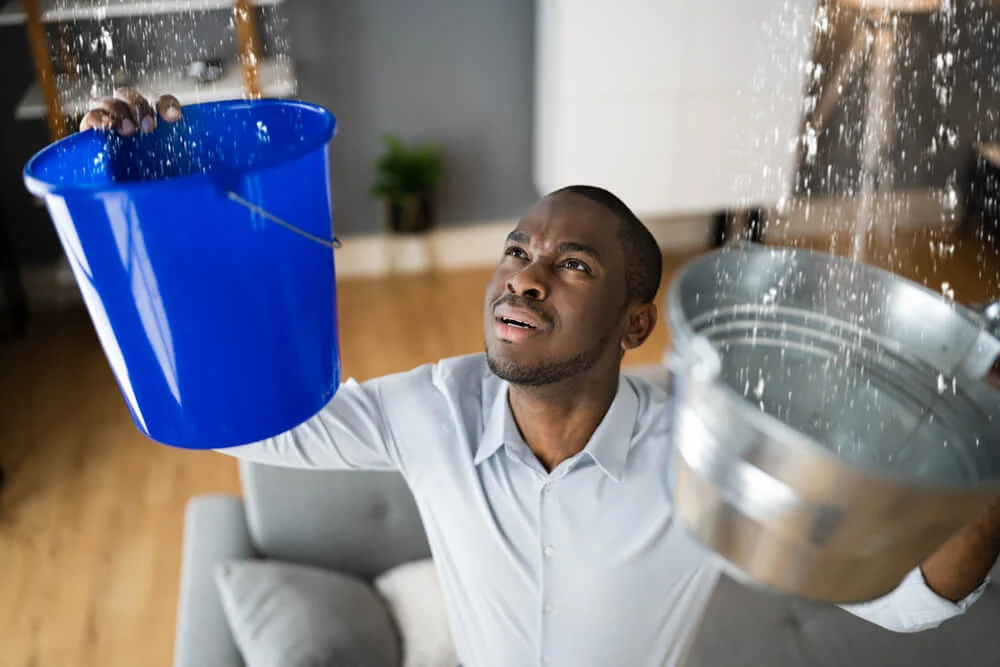 Tenant catching leaking water from an apartment ceiling, a situation that may justify breaking a lease in Georgia