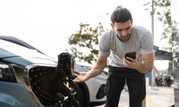 Young man outside car. EV roadside assistance needed for broken car charger problem. Helpless user need help and assistance. Electric car accident. Electric vehicle car trouble.
