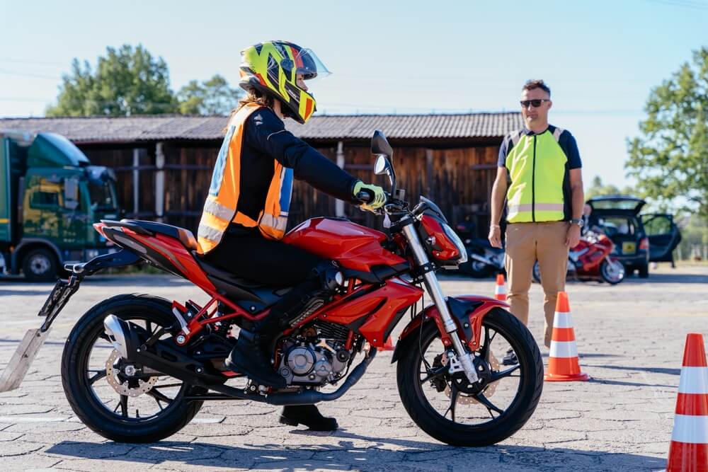 A rider practices basic maneuvers on a motorcycle during a training course in Georgia under instructor supervision