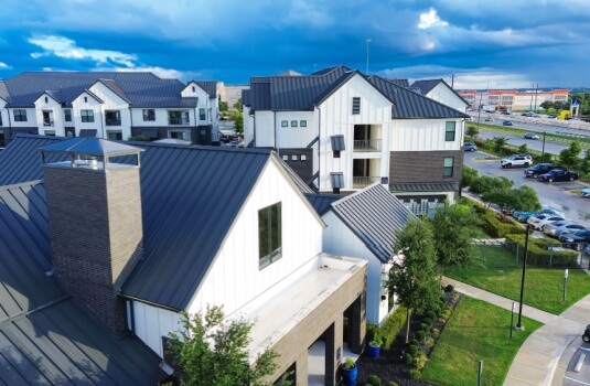 Aerial view of modern homes and condo buildings under a bright sky, visually highlighting the differences in property types often compared in an HO-3 vs HO-6 policy.