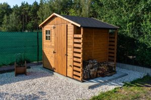 A wooden backyard tool shed with stored firewood, illustrating other structures coverage for detached sheds under a homeowners insurance policy.