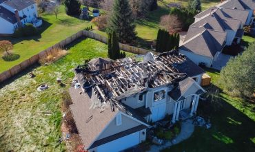 Aerial view of a severely fire-damaged suburban home with a collapsed roof and charred structure, highlighting the importance of Georgia homeowners insurance coverage for property loss and rebuilding.