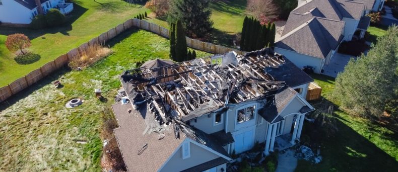 Aerial view of a severely fire-damaged suburban home with a collapsed roof and charred structure, highlighting the importance of Georgia homeowners insurance coverage for property loss and rebuilding.