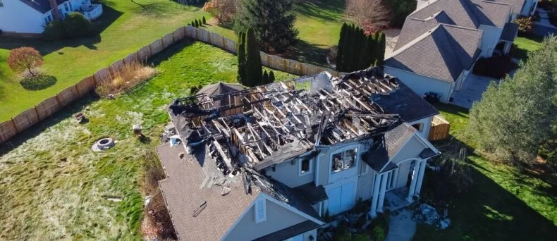 Aerial view of a severely fire-damaged suburban home with a collapsed roof and charred structure, highlighting the importance of Georgia homeowners insurance coverage for property loss and rebuilding.