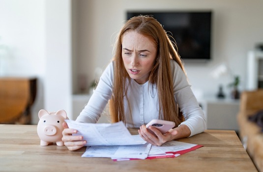 Concerned woman reviewing bills while considering why car insurance is expensive in Georgia.