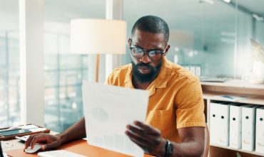 Man reviewing paperwork at his desk while researching why car insurance is expensive in Georgia.