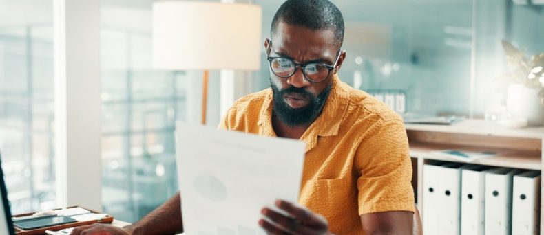 Man reviewing paperwork at his desk while researching why car insurance is expensive in Georgia.