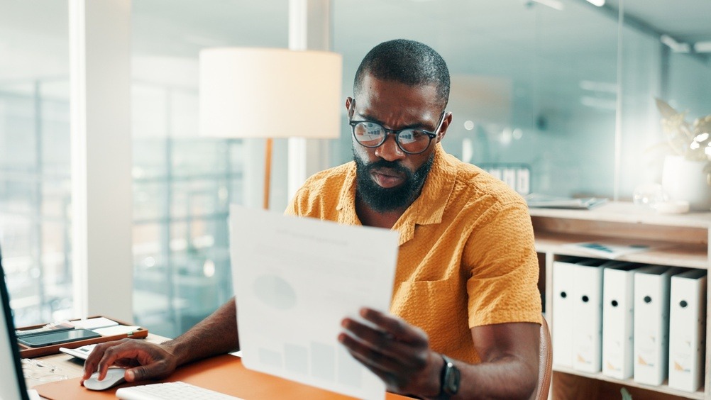 Man reviewing paperwork at his desk while researching why car insurance is expensive in Georgia.