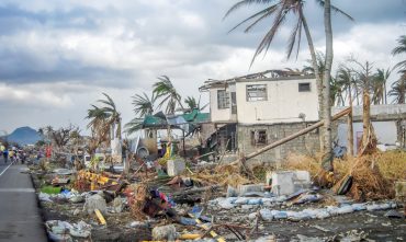 Hurricane damage to a home with debris and fallen palm trees, illustrating renters insurance hurricane damage.