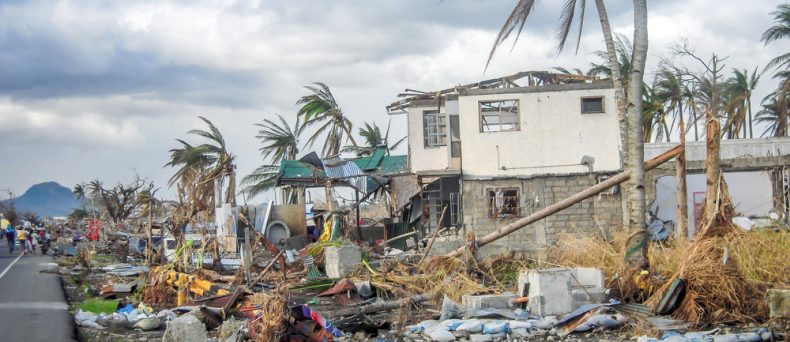 Hurricane damage to a home with debris and fallen palm trees, illustrating renters insurance hurricane damage.