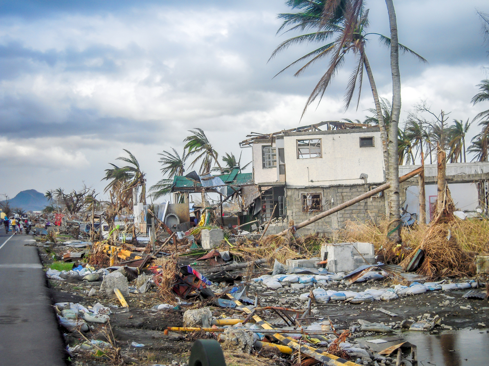 Hurricane damage to a home with debris and fallen palm trees, illustrating renters insurance hurricane damage.