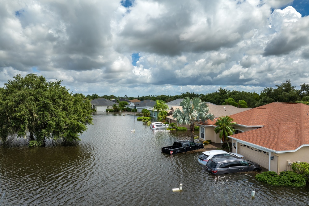 Flooded neighborhood with submerged vehicles and homes, illustrating renters insurance hurricane damage.