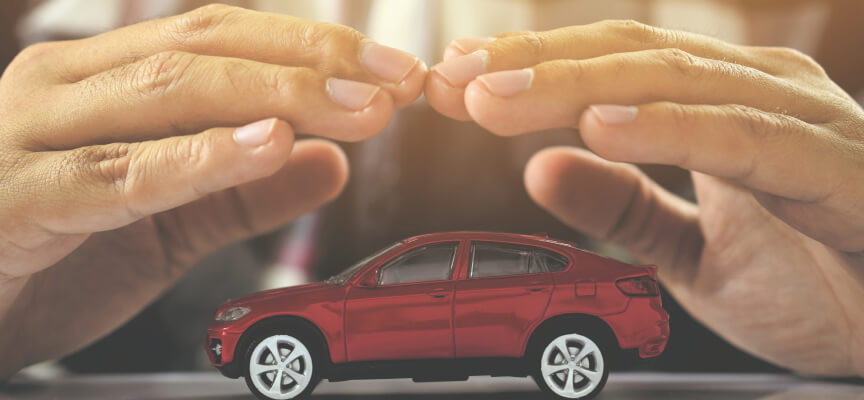 Two hands over a toy car to represent car insurance