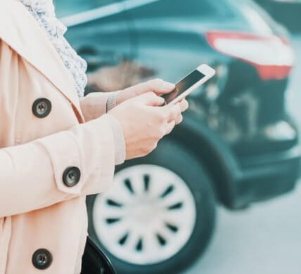 Woman looking at smarphone with a car in the background
