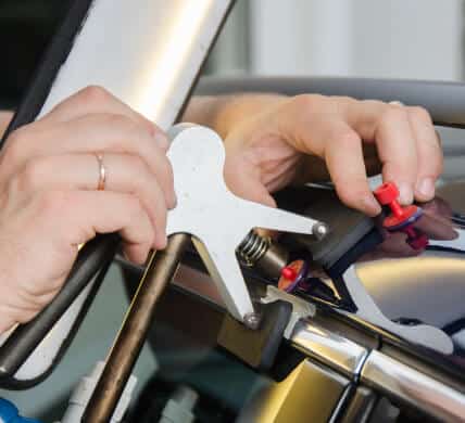 Close up of person fixing a dent in a car using a paintless repair machine