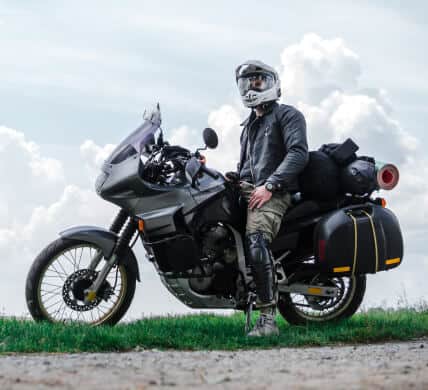 Motorcycle driver with helmet leaning on parked bike