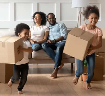 Happy young african american girls playing with boxes with parent in the background