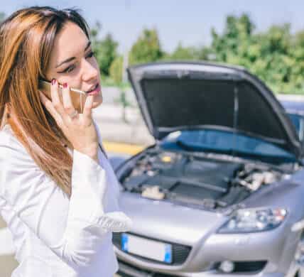 Worried woman on cell phone call with broke down car in the backgorund