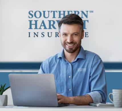 Smiling male southern harvest agent in office with laptop with brand logo in the background