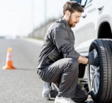 Side view of male mechanic changing a tire on a road