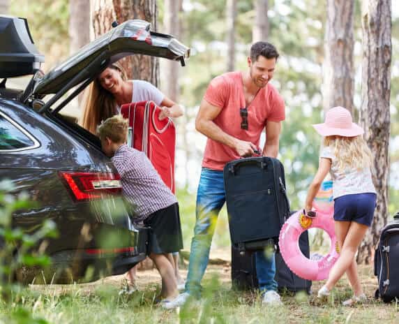 Happy family putting bags in car for a trip