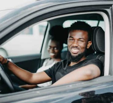 Smiling african american couple inside parked car looking at the camera
