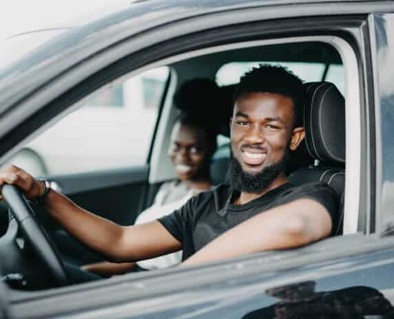 Smiling african american couple inside parked car looking at the camera