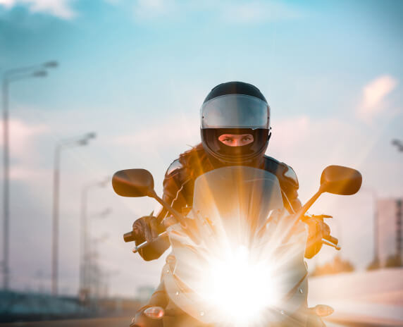 Front view of a man riding his motorcycle with the headlight on