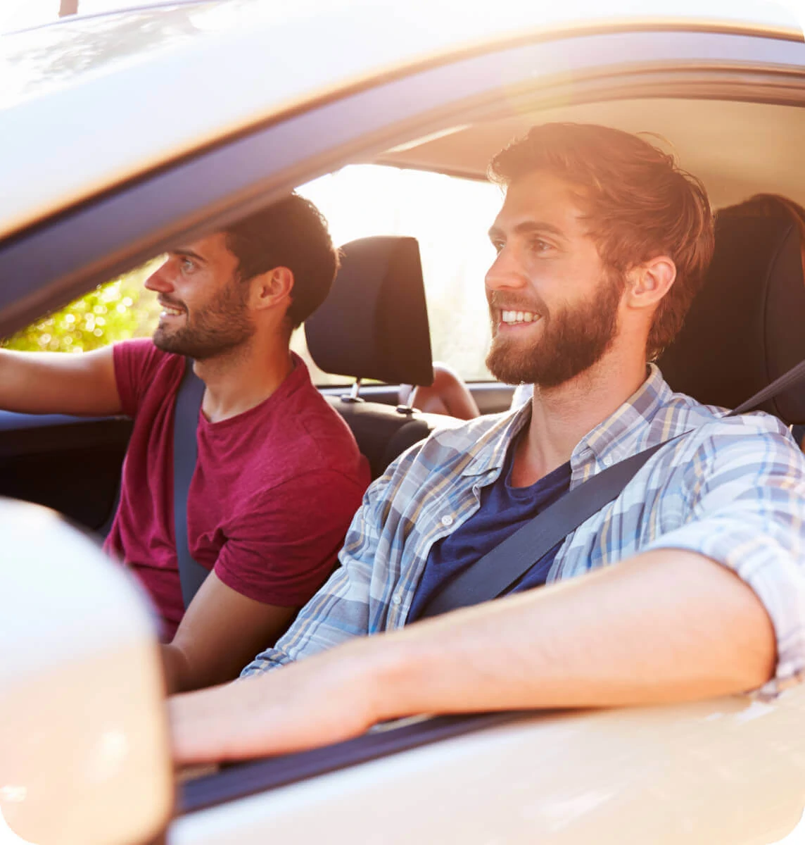 Side view of two smiling men in a car looking at the road.