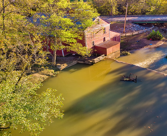 This is a shot taken by a drone of Praters Mill near Dalton Georgia. Looking down from above showing the dam and mill with a road crossing the stream.