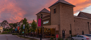 A photo of a bar and grill in a Peachtree Corners shopping center. Setting sun behind colorful clouds in the background.