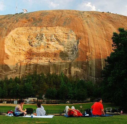 People having a picnic under a large granite carving of Confederate Generals at Stone Mountain near Redan, GA, USA. Cheap car insurance in Georgia.