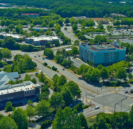 Alpharetta Georgia USA - 8 2 2023: aerial shot of a retail stores and restaurants surrounded by lush green trees and cars driving on the street in Alpharetta Georgia USA